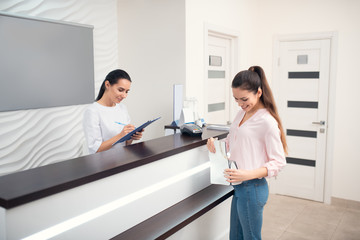 Dark-haired woman smiling while coming to famous beauty clinic