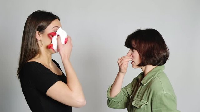 ragazza starnutisce in faccia a una amica che si spaventa e mette la mascherina