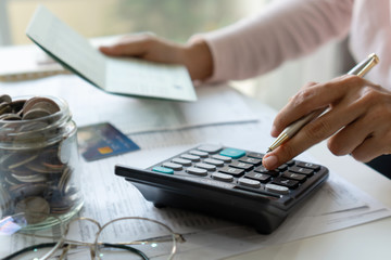 Young Asian woman checking bills, taxes, bank account balance and calculating credit card expenses....