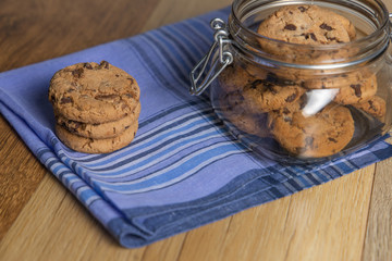 Chocolate cookie jar on rustic wooden background and blue napkin