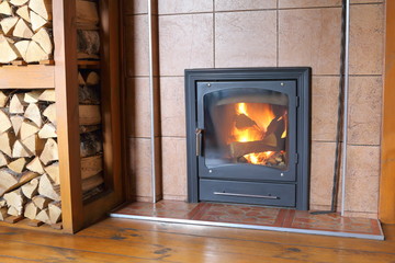 Naklejka premium Fireplace with burning wood in the interior of a rural house.