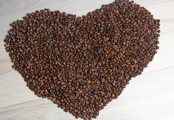 Heart shaped coffee beans on white wooden background