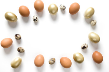 Easter frame of golden, quail, chicken eggs on white. View from above. Space for text.