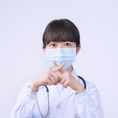 Young female doctor woman wearing mask, making stop sign gesture, saysignaling No isolated on white...