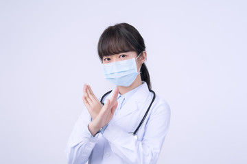 Young female doctor woman wearing mask, making stop sign gesture, saysignaling No isolated on white...