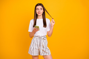 Photo of attractive lady hold telephone hands look empty space wounding curl around finger wear casual white t-shirt striped summer shorts isolated vibrant yellow color background