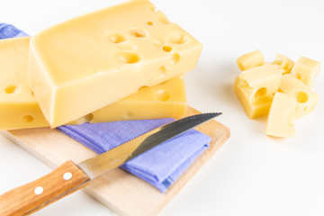 Fresh cheeses of different flavors with nuts on black chalkboard plate and wooden board on white commercial background and space for text