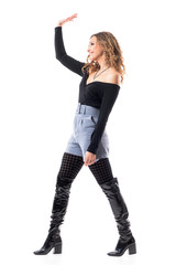 Fototapeta premium Side view of young stylish modern woman walking and waving hand greeting someone. Full body length isolated on white background. 