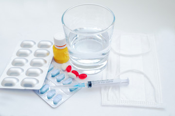 Medical examination and treatment concept. Red and white pills, thermometer, yellow serum, mask, a medical syringe on a blue background top view copy space. Medical flat lay
