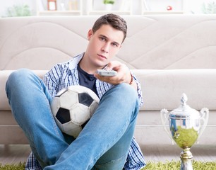 Young man student watching football at home