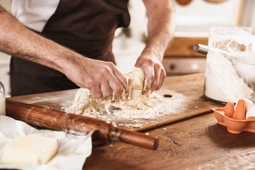 Cropped image of caucasian man in apron cooking dough