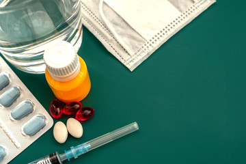 Medical examination and treatment concept. Red and white pills, thermometer, yellow serum, mask, a medical syringe on a blue background top view copy space. Medical flat lay