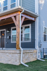 View of a porch with decorative painted wooden beams holding the roof with a gutter system running...