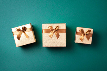 Gift box with sparkling gold glitter on green background. Romantic card. New year, Christmas, Valentine's day concept of greetings. Copy text. Top view, flat lay.