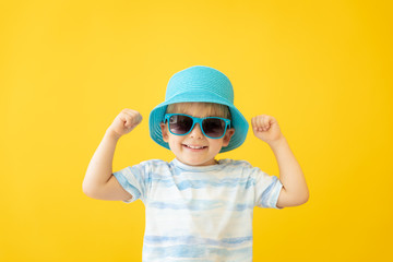 Portrait of happy child against yellow background. Summer vacation concept