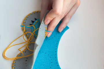 A girl sews an owl toy from felt. Cute stuffed toy is made manually. Easy sewing project for kids