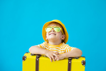 Portrait of happy child with yellow suitcase. Summer vacation concept