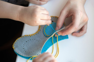 Сhild is sewing a toy owl from felt. Children's needle in their hands. Cute stuffed toy is made manually. Easy sewing project for kids.