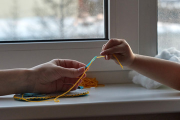 Сhild is sewing a toy owl from felt. Mother teaches the child to sew. 