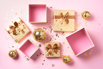 Gift box, shiny gold disco balls, sparkling gold glitter on pink background. New year baubles, star...