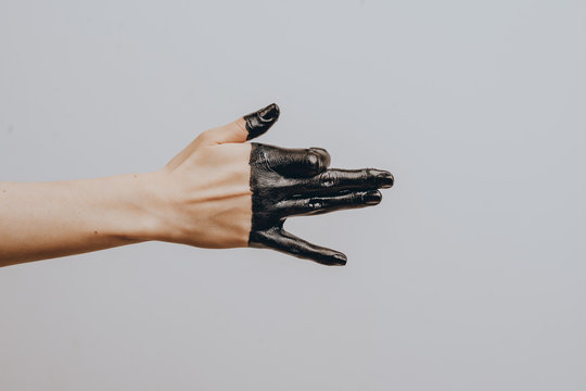 Elegant female hand dipped in black paint on a light background. Isolated. Gesture.