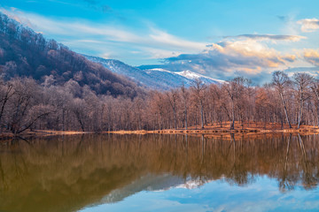 Beautiful spring landscape. Forest on the lake, the trees and mountains reflacted on the water. 