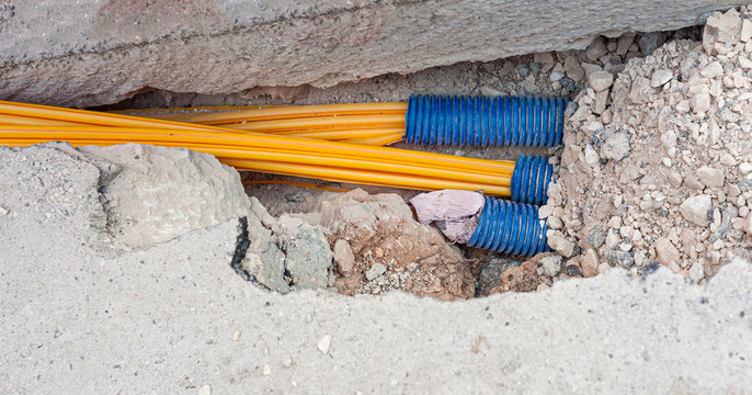 Worker inserts fiber optic cables buried in a micro trench