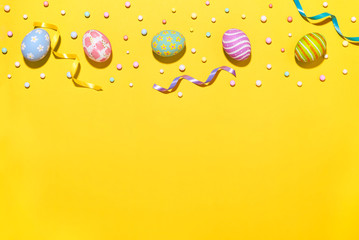 Creative Easter holiday layout eggs colored handmade paint ed with ribbon foam party on yellow background.Seasonal flat lay concept.