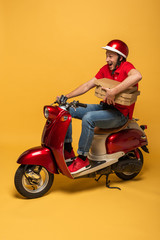 excited delivery man in red uniform holding pizza boxes on scooter on yellow background