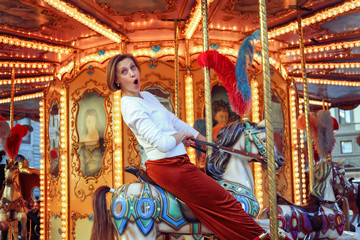 Fototapeta na wymiar Woman riding on a traditional vintage carousel in a city park