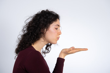 A woman blowing a kiss out of her hand palm in a positive and expressive pose
