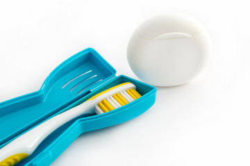 Toothbrush in a plastic case and dental floss on white background