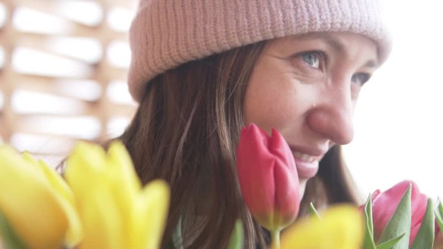 A beautiful woman sniffs a bouquet of tulips donated on a woman's day. Congratulations on the holiday