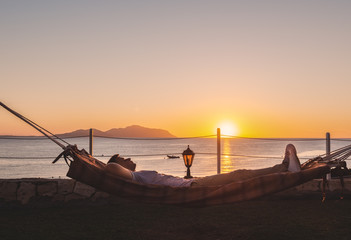 A man in a hammock near the sea at sunrise