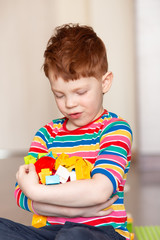 red-haired boy in a multi-colored sweater holds in his hand a lot of multi-colored and bright designer, smiles