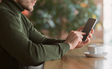 Cropped of man using smartphone at cafe