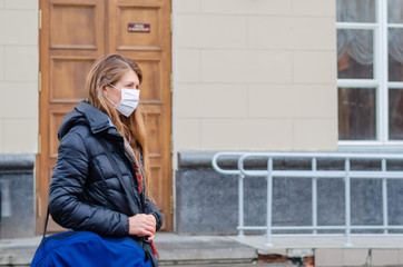 Traveler european woman wears medical mask to protect against coronavirus or flu on public transport station. Prevention in public spaces.