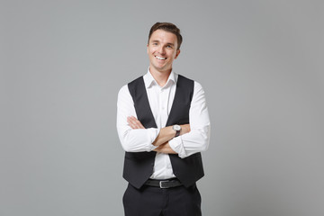 Smiling young business man in classic black waistcoat shirt posing isolated on grey wall background...