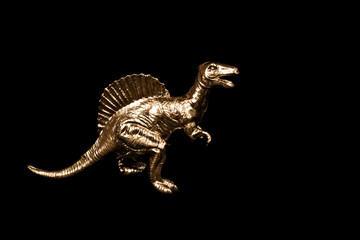 Fototapeta na wymiar Golden toy dinosaur isolated on black background.