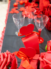 Closeup of red rose leaves, heart shaped red boxes and wine glasses. Selective focus.