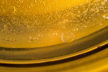 Yellow oil bubbles on water, cooking oil background.