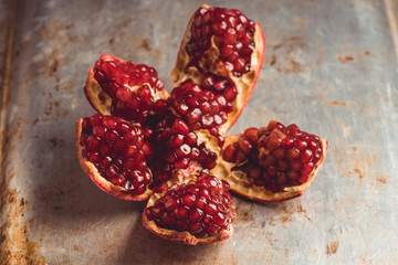 Broken red ripe pomegranate fruit on the dark rustic background. Selective focus. Shallow depth of field.
