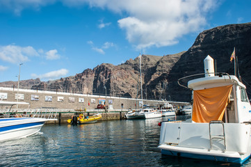 Marina in the port of Los Gigantes. Sea boats and view of the rock formation - the Giants cliffs.