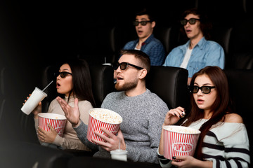 Terrified audience in 3D glasses on scary movie premiere in cinema