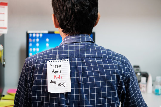 Back Of Young Man Office With A White Paper Note Attached With The Text Happy April Fools Day