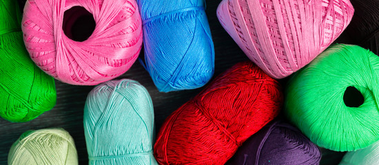 close up dark shadow background made of collection of colorful yarn rolls of natural material