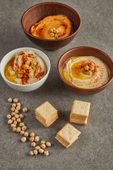 Bowls with tasty hummus with chickpea and crackers on grey background