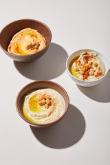 Bowls with delicious hummus and chickpea on grey background