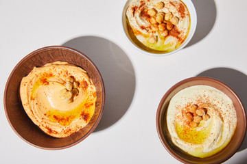 Top view of bowls with hummus and chickpea on grey background