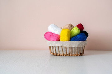 some different colorful yarn rolls in the basket on shelf or table at home, homemady hobby